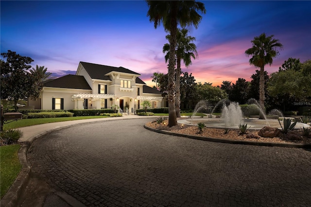 view of front of house featuring curved driveway and stucco siding