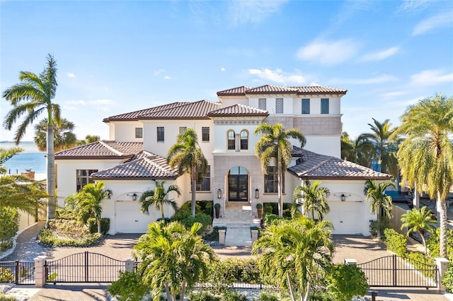 mediterranean / spanish house featuring a garage, a gate, decorative driveway, and a fenced front yard