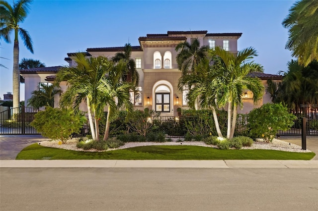 mediterranean / spanish-style house with a gate, fence, and stucco siding