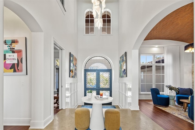 dining space with baseboards, arched walkways, wood finished floors, and french doors