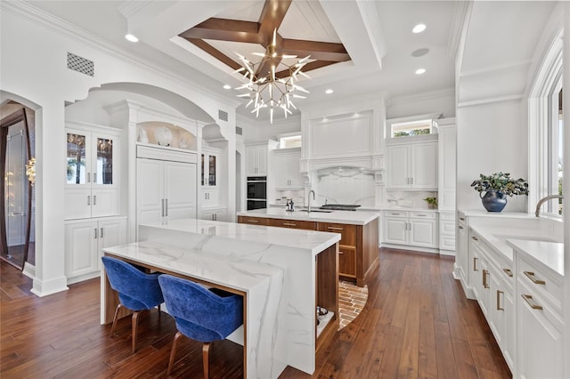 kitchen with dark wood-style flooring, visible vents, decorative backsplash, a kitchen island with sink, and white cabinets