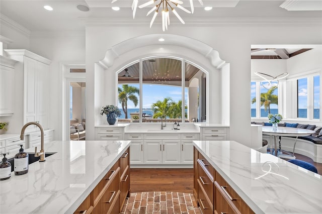 kitchen with white cabinetry, a chandelier, and light stone counters