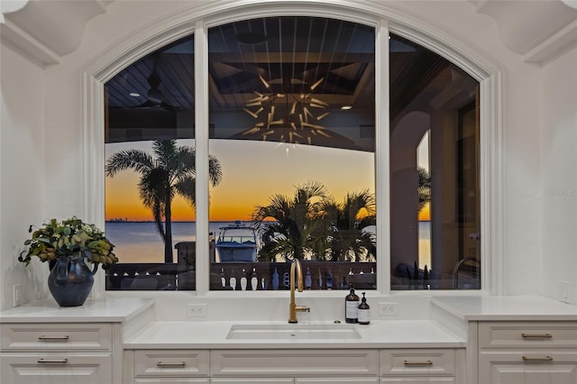 interior space with white cabinets, a sink, and light countertops