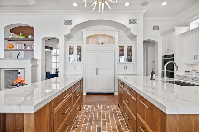 kitchen featuring light stone countertops, a spacious island, visible vents, and a sink