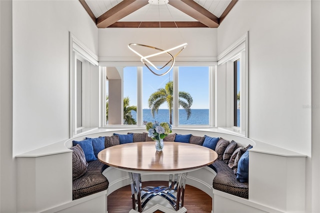 dining area featuring a water view, breakfast area, beamed ceiling, and wood finished floors