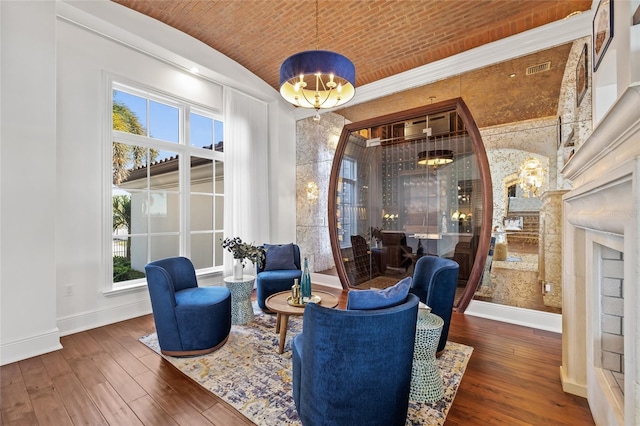 sitting room featuring a notable chandelier, lofted ceiling, brick ceiling, baseboards, and hardwood / wood-style flooring