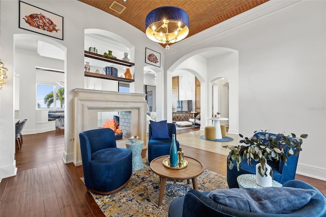 sitting room featuring arched walkways, visible vents, baseboards, built in features, and wood-type flooring