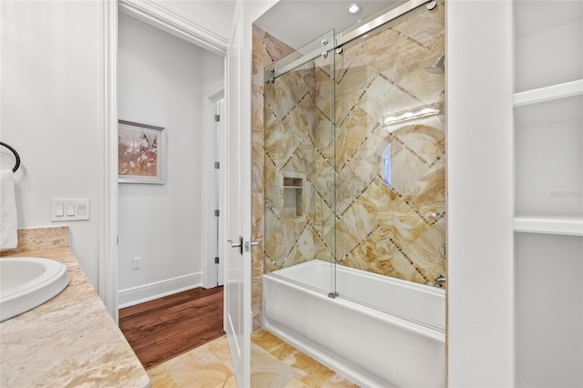 bathroom with shower / bath combination with glass door, wood finished floors, vanity, and baseboards