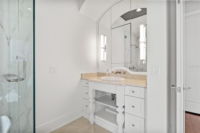 bathroom featuring baseboards, vanity, a marble finish shower, and tile patterned floors