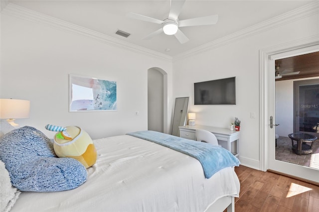 bedroom featuring baseboards, visible vents, arched walkways, ornamental molding, and wood finished floors