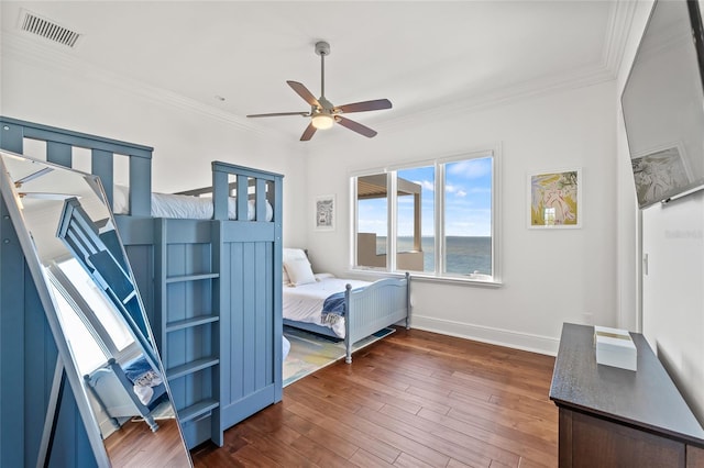 bedroom with baseboards, visible vents, ceiling fan, wood finished floors, and crown molding