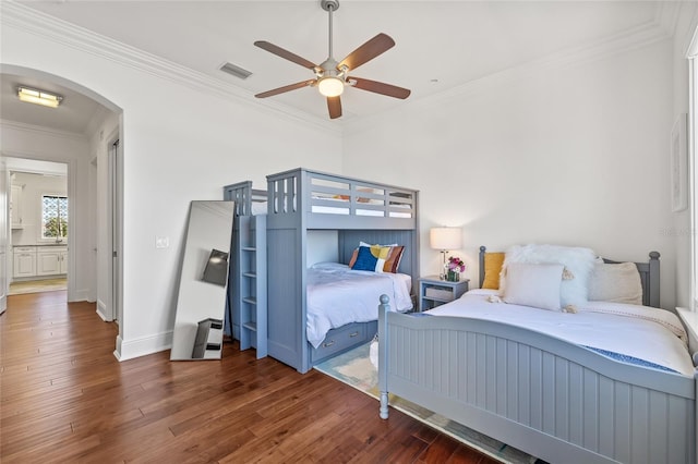 bedroom with arched walkways, wood finished floors, visible vents, baseboards, and crown molding