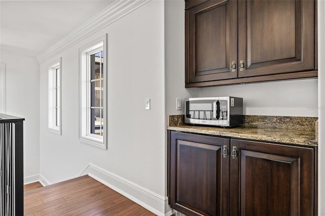 bar featuring ornamental molding, stainless steel microwave, wood finished floors, and baseboards