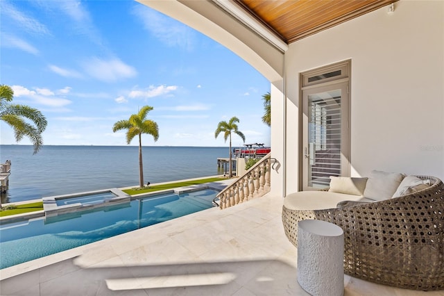 balcony with a water view, a patio area, and a pool with connected hot tub