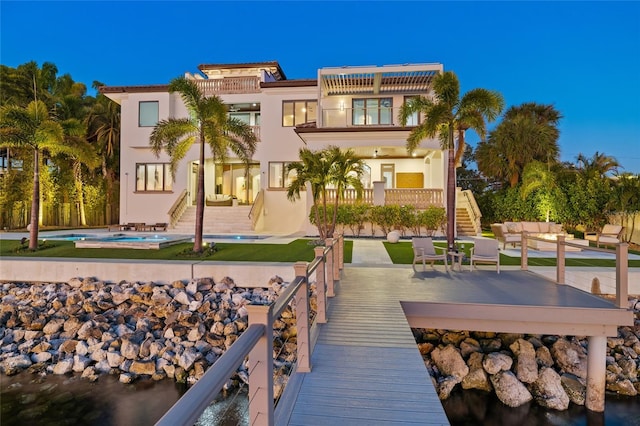 back of property with stucco siding, an outdoor hangout area, a patio area, a balcony, and stairs