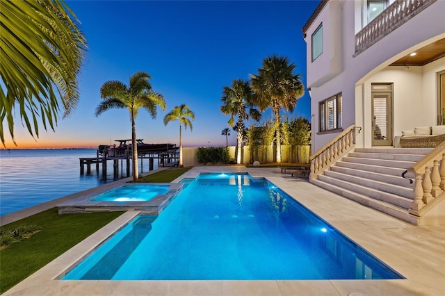 view of pool featuring a water view, a pool with connected hot tub, fence, and a patio