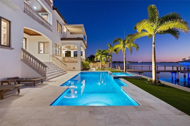 pool at dusk featuring stairway, a patio area, and a pool with connected hot tub