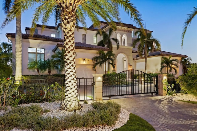 view of front of house featuring a gate, fence, a tiled roof, and stucco siding