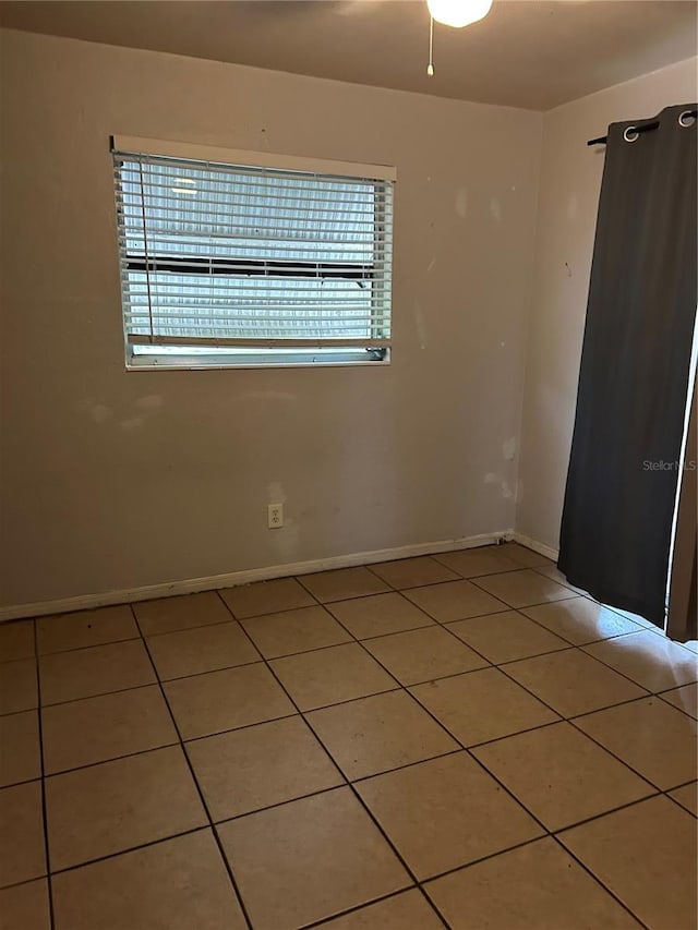 unfurnished room with light tile patterned floors and baseboards