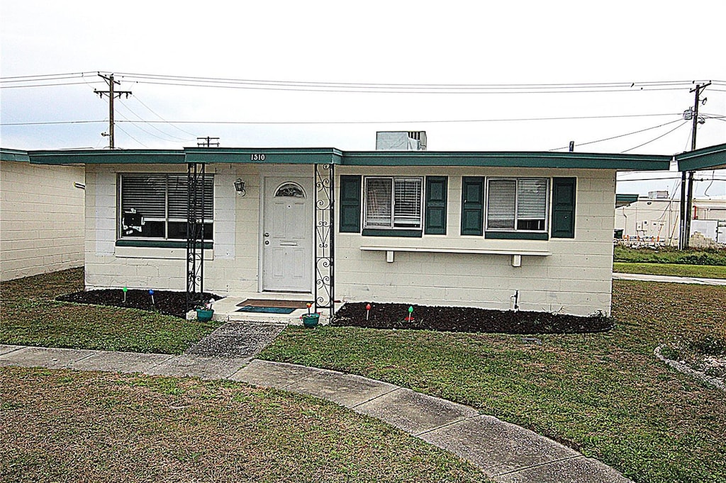 view of front of property featuring a front yard and concrete block siding