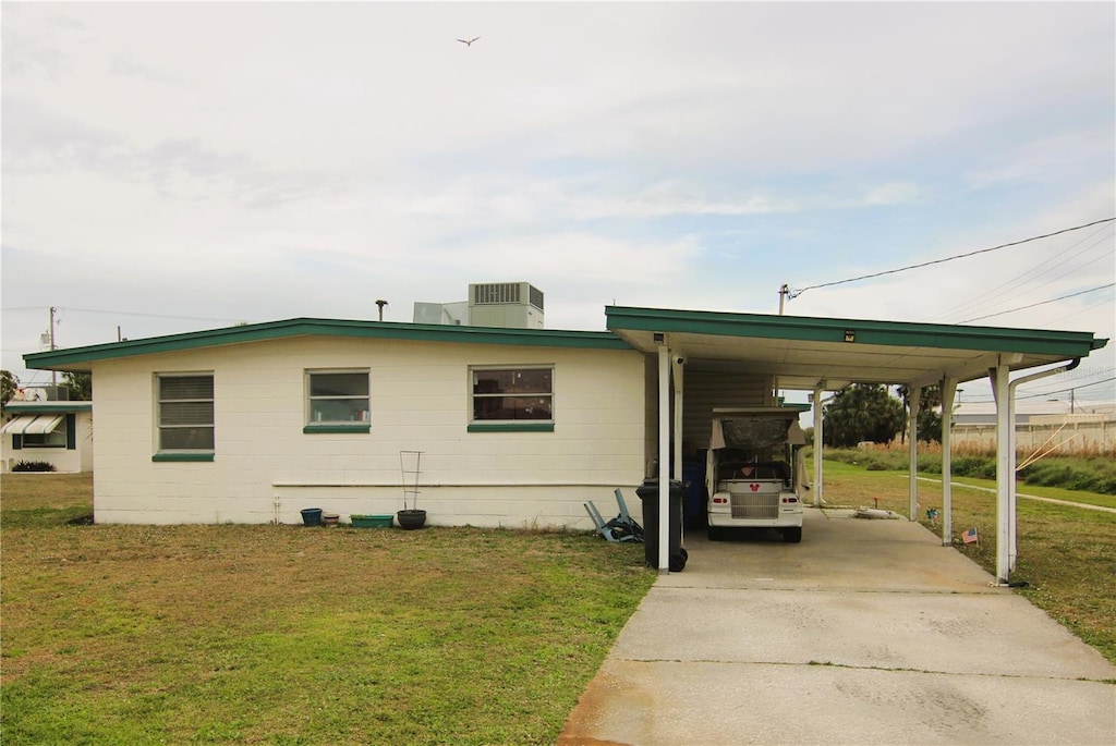 view of front of property featuring an attached carport, driveway, a front lawn, and central AC unit