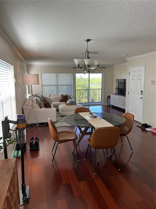 dining area with hardwood / wood-style flooring, ornamental molding, a chandelier, and a textured ceiling