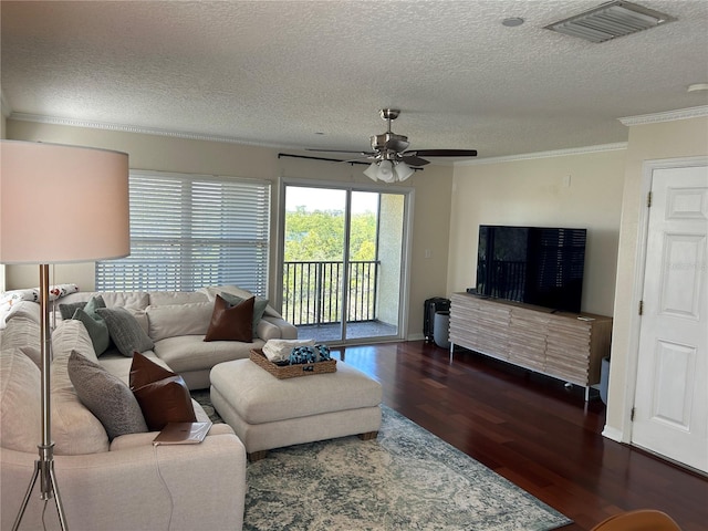 living room featuring dark wood-style floors, visible vents, ornamental molding, a ceiling fan, and a textured ceiling