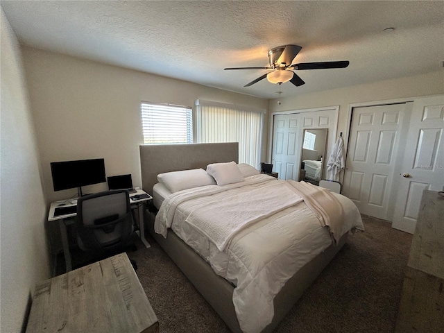 carpeted bedroom featuring a textured ceiling, ceiling fan, and multiple closets