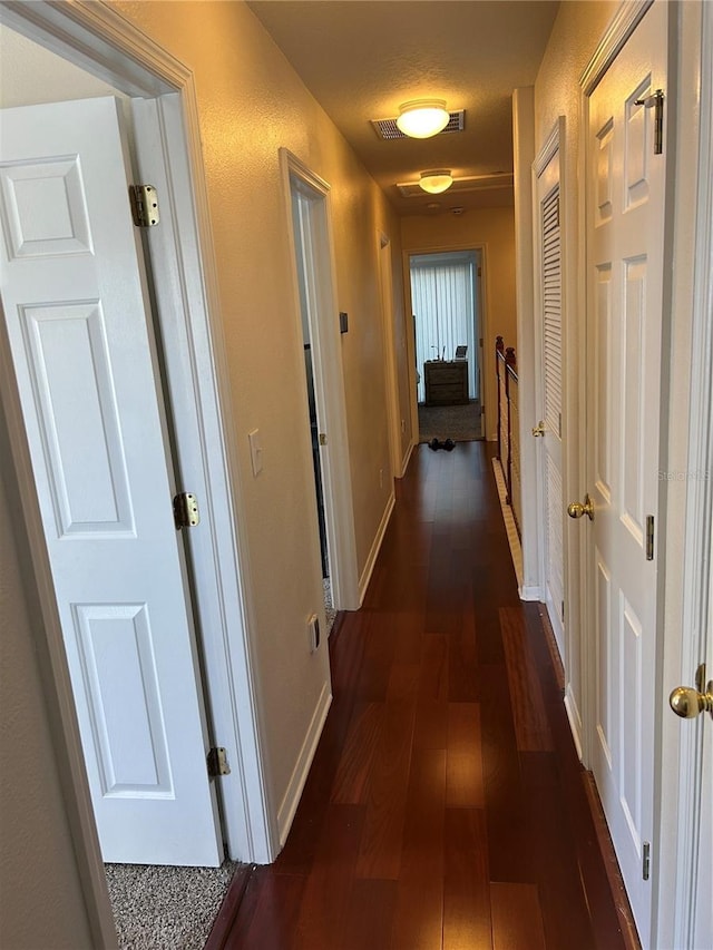 corridor featuring dark wood-type flooring and baseboards