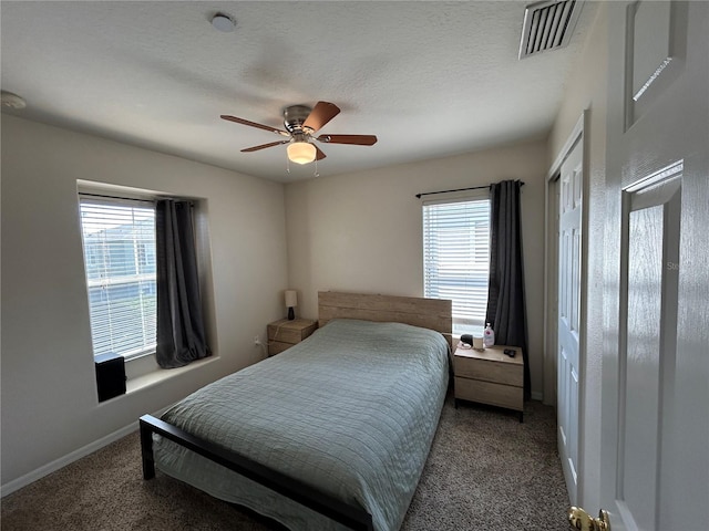 carpeted bedroom with visible vents, a textured ceiling, baseboards, and multiple windows