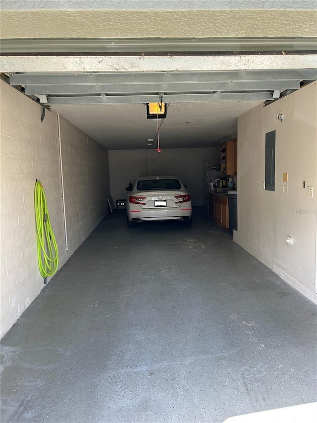 garage featuring a garage door opener, concrete block wall, and electric panel