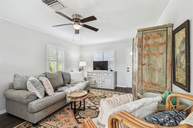 living area with baseboards, ceiling fan, visible vents, and dark wood-style flooring