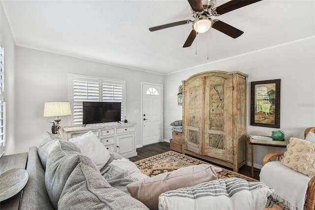 living area with a ceiling fan, dark wood finished floors, baseboards, and ornamental molding