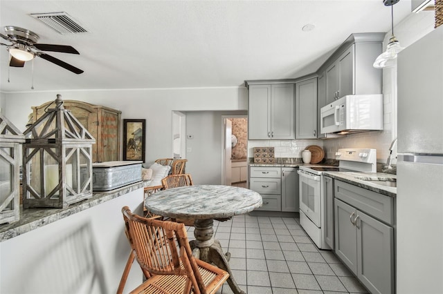 kitchen with white appliances, light tile patterned floors, visible vents, decorative backsplash, and gray cabinetry