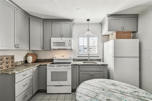 kitchen featuring white appliances, decorative backsplash, a sink, and gray cabinetry