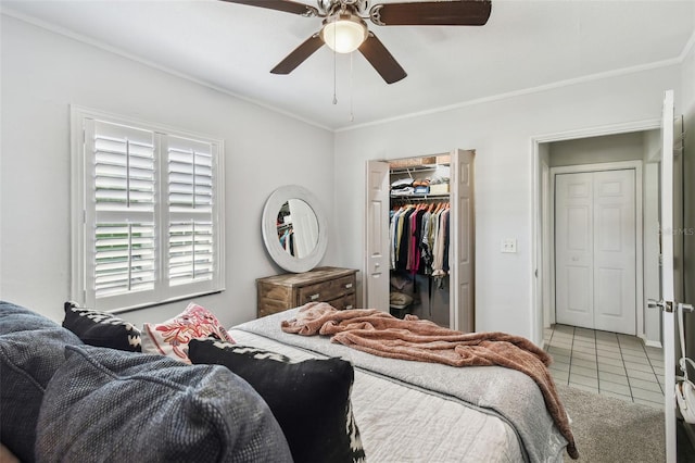 bedroom featuring ceiling fan, ornamental molding, tile patterned floors, a walk in closet, and a closet