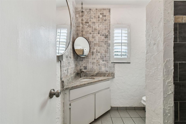 half bathroom featuring a textured wall, toilet, tile patterned flooring, crown molding, and vanity