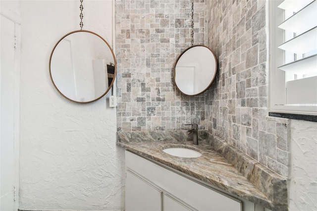 bathroom featuring a textured wall, backsplash, and vanity