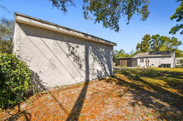 view of property exterior featuring a yard, an outbuilding, and stucco siding