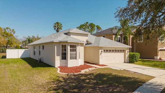 view of front of house featuring stucco siding, a front yard, fence, a garage, and driveway