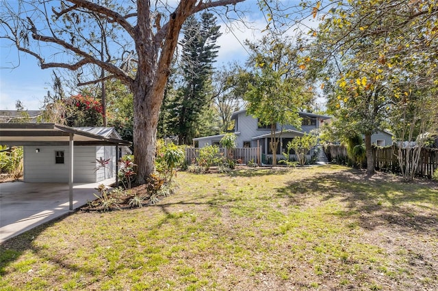 view of yard featuring driveway, a carport, and fence