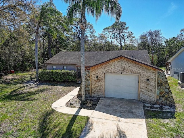 view of front facade with a front yard, roof with shingles, driveway, and an attached garage