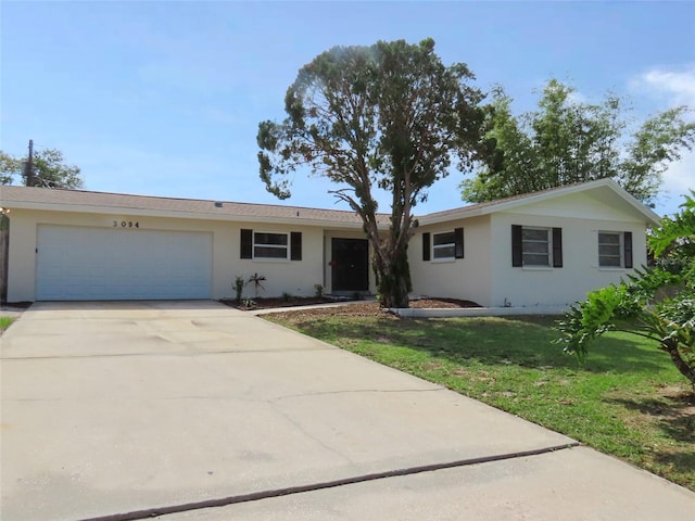 single story home featuring a garage, stucco siding, driveway, and a front yard