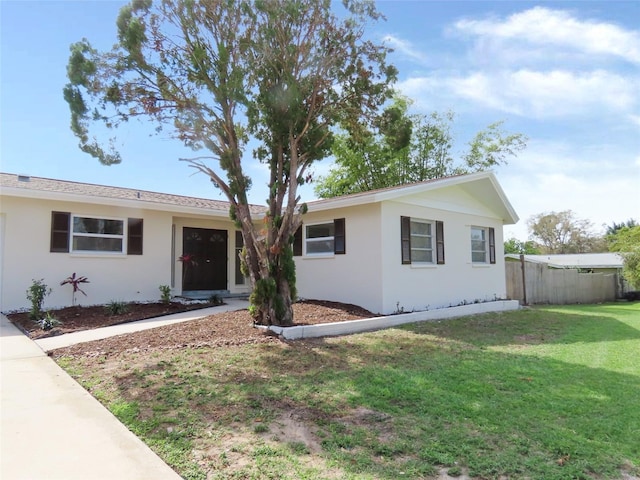 ranch-style home with stucco siding, fence, and a front yard