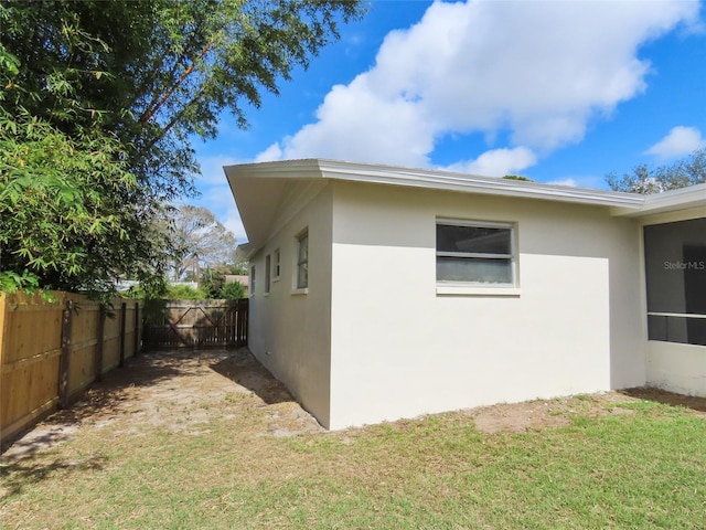 view of property exterior featuring a yard, fence, and stucco siding