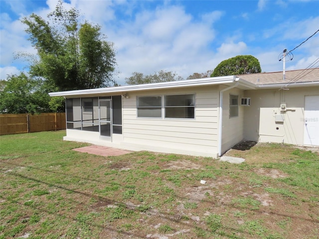 rear view of house with a sunroom, fence, and a yard