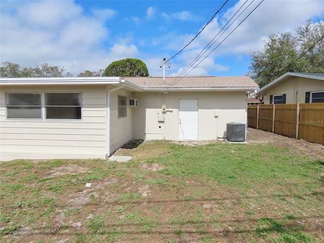 rear view of house featuring a lawn, fence, and central air condition unit