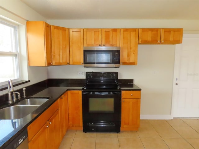 kitchen featuring appliances with stainless steel finishes, brown cabinetry, light tile patterned flooring, and a sink