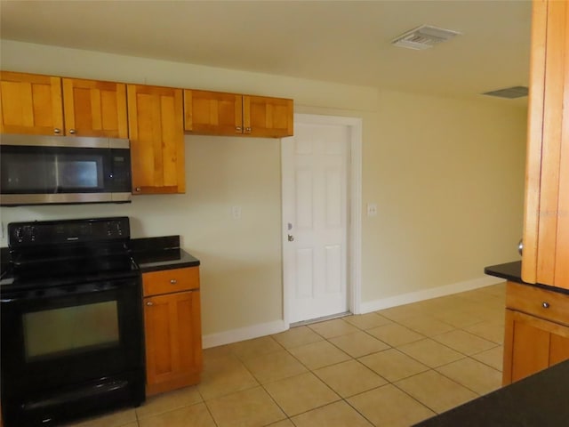 kitchen featuring electric range, visible vents, brown cabinets, stainless steel microwave, and dark countertops