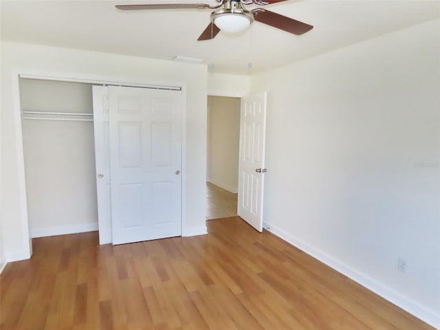 unfurnished bedroom with light wood-type flooring, a ceiling fan, baseboards, and a closet